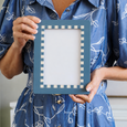 Person holding the Barnet Blue Check Photo Frame 4x6 inch, showcasing its coastal blue resin finish and checkerboard border, ideal for Hamptons and coastal home décor.