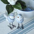 Beach Birds Set of 2 styled on a blue and white striped table runner with white magnolia flowers and coastal ceramics.