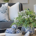 Bellamy Garden Coastal Blue cushions styled on a sofa with blue and white ceramics and green foliage in a Hamptons living room.