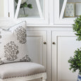 Bellamy Garden Cushion Sage Green styled on a white chair beside a green topiary