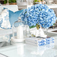 round marble tray styled on coffee table with blue hydrangeas candle and books coastal living room