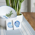 Blue Bay Stripe Chambray Table Runner styled with blue and white bowls, shell coasters and white orchids on a timber table.