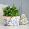 Blue Floral Herb Planter Bowl styled with greenery beside a decorative botanical vase on a shelf.