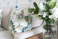 Blue Sapphire floral cushion styled on a light sofa beside fresh white hydrangeas in a coastal living space
