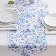 Blue and white floral table runner and matching coasters styled on a Hamptons-inspired dining table with white dinnerware and glassware
