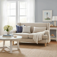 Bondi Hamptons 2 Seat Sofa styled in a light coastal living room with blue and white cushions, neutral throw and natural rug.