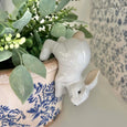 Bunny Pot Sitter White styled on a blue floral planter with eucalyptus greenery
