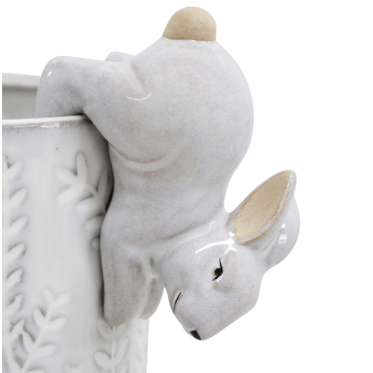 White ceramic bunny pot sitter ornament perched on the edge of a decorative planter