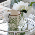 White ceramic bunny pot sitter decorating a botanical planter on a mirrored tray beside white hydrangeas