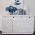Blue and white motif canisters styled on a white sideboard with hydrangeas and coastal botanical artwork.
