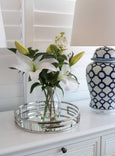 White lily artificial arrangement in glass vase styled on console with ceramic lamp