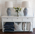 Casablanca lily faux arrangement styled between blue and white lamps on console table