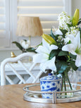 Faux Casablanca lily arrangement styled on tray with blue and white decor on wooden table
