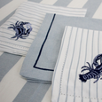 Chambray Stripe Blue Bold Stripe tablecloth styled with embroidered coastal napkins and linen placemats for a Hamptons-inspired dining setting.