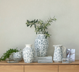French-inspired floral porcelain vase styled on a timber console with greenery and decorative accents