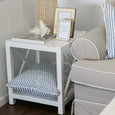 Blue cushion styled on a side table shelf in a coastal interior with lamp and decor