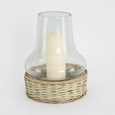 Glass chimney hurricane lantern with woven wicker base styled with white LED pillar candle