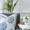 Coastal Pearl Table Lamp with white shade and textured ceramic base beside a blue sofa, blue floral cushion, white orchids and a white round side table.
