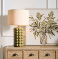 Close-up of Condetti green table lamp featuring raised spherical ceramic detailing and neutral linen shade
