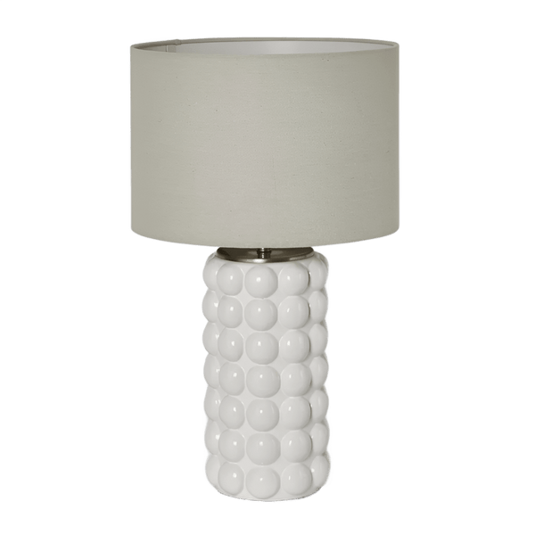 Condetti white ceramic table lamp with raised spherical detailing and natural linen shade on a side table