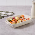 Cream speckled stoneware baking dish styled with roasted vegetables on a kitchen benchtop