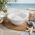 Dragonfly Stoneware White Salt Bowl filled with sea salt and styled on a coastal dining table, showing dimensions of 11cm diameter and 5cm height alongside natural woven placemats, seashell décor and ocean-inspired styling.