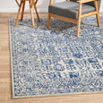 Eve Blue Rug styled beneath timber armchair and side table in a relaxed coastal interior