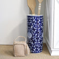 Blue and white Fleur Umbrella Stand styled in a Hamptons-inspired interior holding decorative timber paddles beside a white console cabinet.
