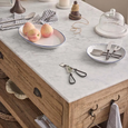 Glass cloche styled on marble kitchen bench with fruit and tableware