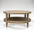 French Contemporary Round Coffee Table in weathered oak displayed in studio setting with round top and lower shelf.