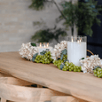 Glass triflame LED candles styled on a timber dining table with greenery and hydrangeas for warm ambient entertaining décor.