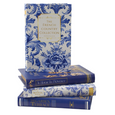 Four decorative Hamptons book boxes displayed upright showing blue and white floral and navy book spines with gold lettering.