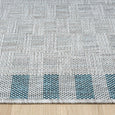 Close-up of Haven Blue Outdoor Rug showing textured grey weave and coastal blue border