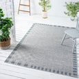 Haven Blue Outdoor Rug styled in a light covered patio with outdoor furniture and greenery