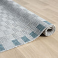 Rolled Haven Blue Outdoor Rug showing low-profile flat-weave construction and blue border