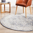 Hunter Ocean Round Rug styled beneath a leather accent chair and timber side table in a contemporary coastal living room.