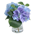 Artificial lavender and blue hydrangea arrangement in a clear glass vase with realistic faux water for Hamptons and coastal home styling.