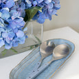 Blue faux hydrangea arrangement styled beside a Capri blue ceramic platter for coastal tabletop decor.