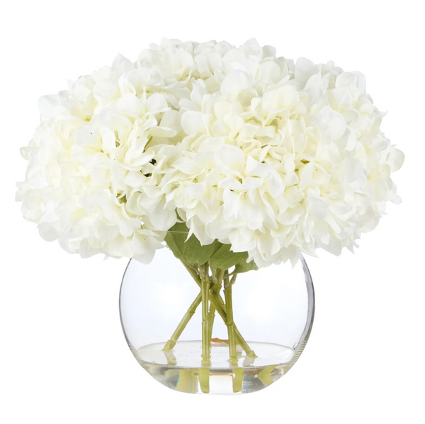 White everlasting hydrangea arrangement in a clear Phoebe Sphere glass vase with lifelike green stems and faux water.
