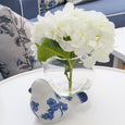 White hydrangea in glass sphere vase styled on table with blue and white decor