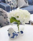 White hydrangea in glass sphere vase styled on table with blue and white decor