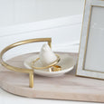 White ceramic bird trinket dish styled with gold jewellery and a decorative photo frame on a soft coastal bedside setting.