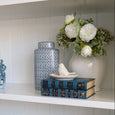 White ceramic bird trinket dish styled on Hamptons shelving with blue books, florals and coastal décor accents.