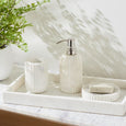 White marble soap dish styled with matching tumbler and soap dispenser on a coastal bathroom vanity tray.