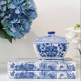 Blue and white Ming-style ceramic trinket jar styled on decorative books beside blue hydrangeas in a Hamptons-inspired interior.