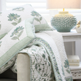 Kaya Hand Block Print Cotton Bedspread styled on a coastal bed with matching pillow shams and seafoam ceramic table lamp.