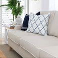 Knightsbridge natural linen sofa layered with navy and blue patterned cushions in a relaxed coastal interior.