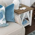 Close-up of Knightsbridge natural linen sofa with blue cushions and white piping in a coastal living room.