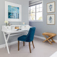 Laguna Cross Leg Stool handcrafted from woven water hyacinth styled in a Hamptons home office beside a white desk, blue upholstered chair and coastal artwork.