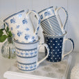 Stacked Le Petite blue and white ceramic mugs showcasing the four coordinating assorted patterns in a Hamptons kitchen setting.